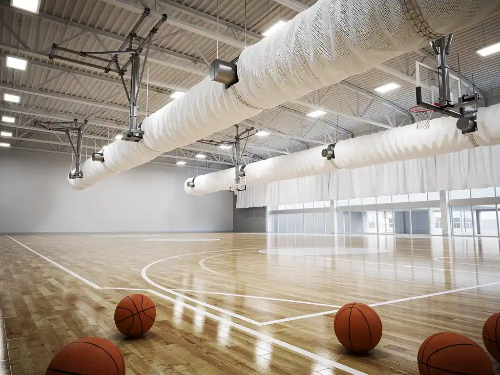 Moderne sporthal met witte stoffen luchtkanalen aan plafond boven basketbalveld, LED-verlichting en gepolijste houten vloer