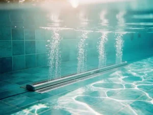 Zwembad met luchtsok diffuser systeem dat belletjes produceert onder kristalhelder turquoise water in mediterraans zonlicht