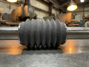 Stoffen balgsluiting op maat om gepolijste industriële as op stalen werkbank in productieomgeving.
